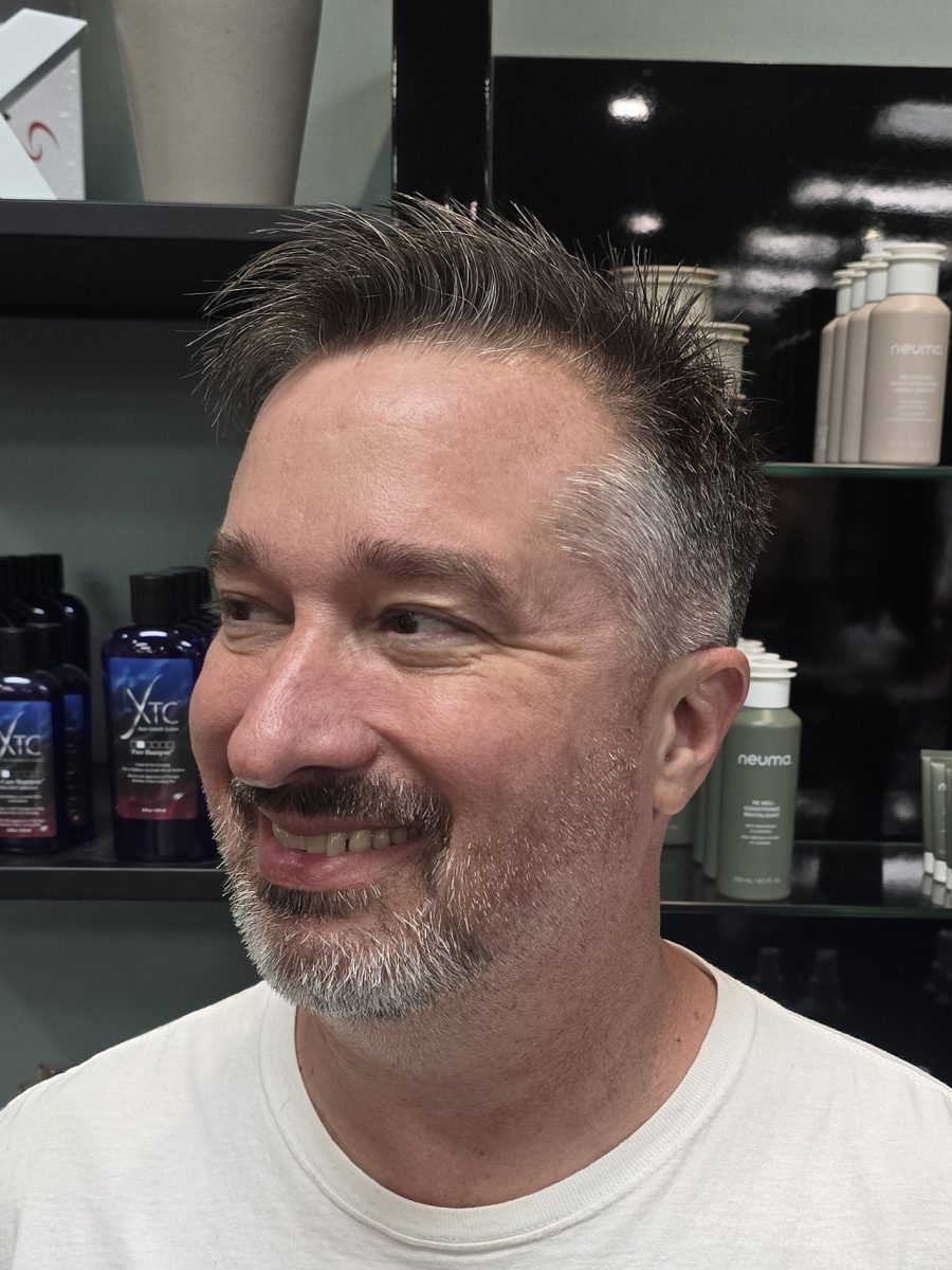Man with dark hair styled in a fade cut, three-quarter profile view, by Kristan Sayers at K Bella Hair Studio & Spa in Brighton, MI
