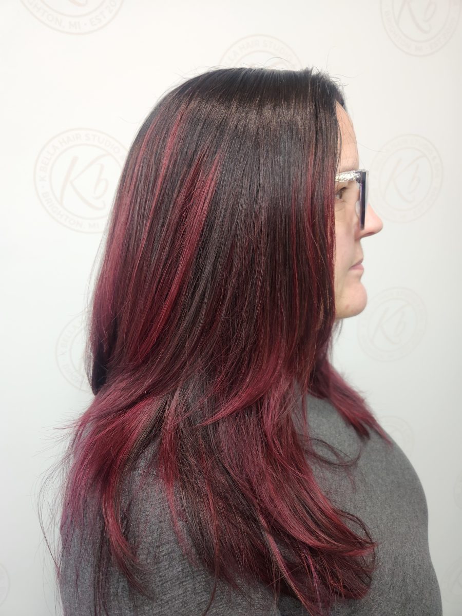 Side profile showing tapered layers and burgundy color blend with dark roots by Siobhan Rozinski at K Bella Hair Studio & Spa in Brighton, MI