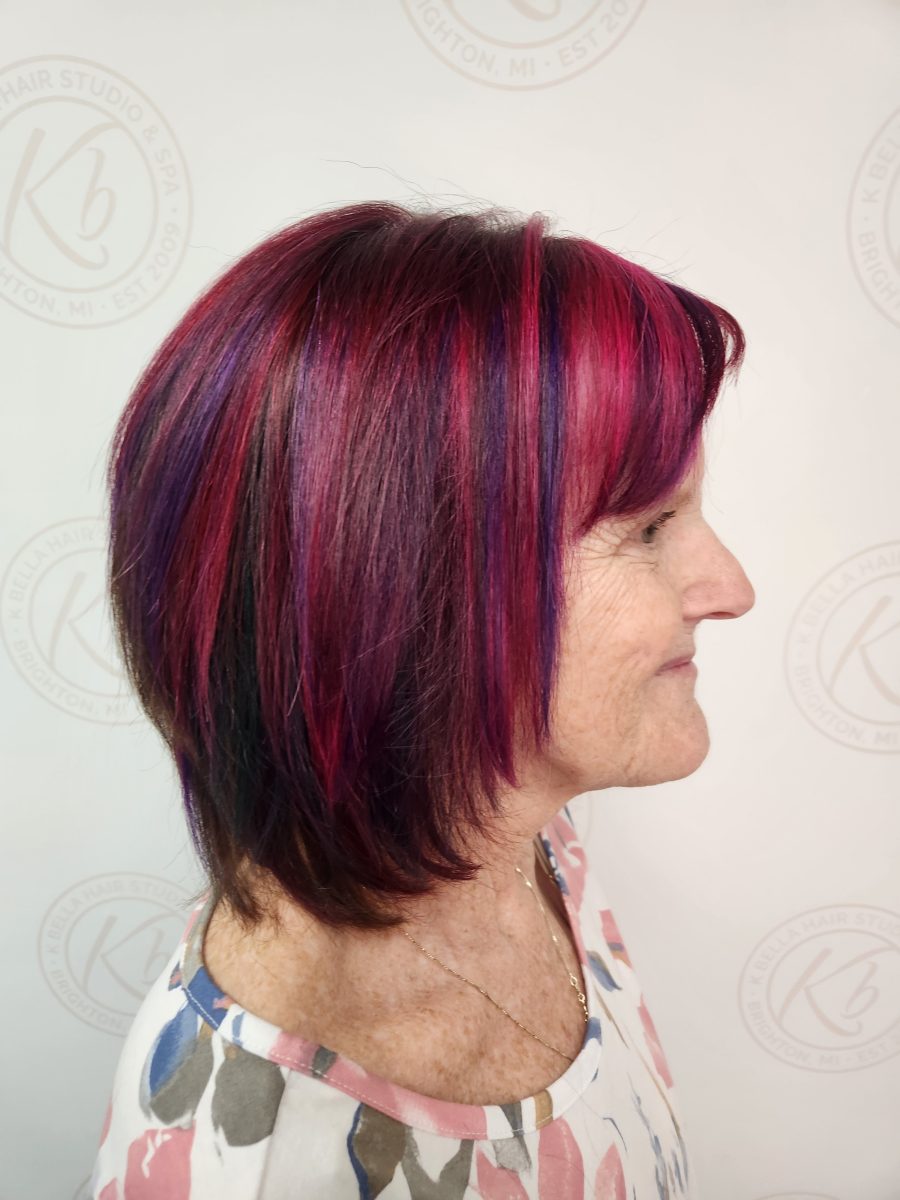 Side profile of chin-length layered haircut with plum and magenta color by Siobhan Rozinski at K Bella Hair Studio & Spa in Brighton, MI