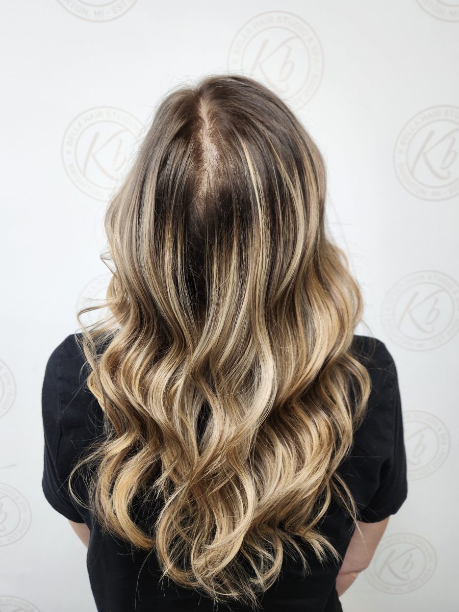 Back view of long wavy hair with multidimensional balayage highlights and textured layers by Siobhan Rozinski at K Bella Hair Studio & Spa in Brighton, MI