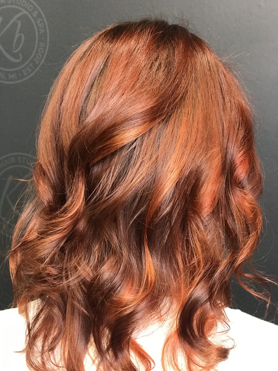 Close-up of shoulder-length hair with layered copper and chocolate tones in soft waves by Allison Bowsher at K Bella Hair Studio & Spa in Brighton, MI