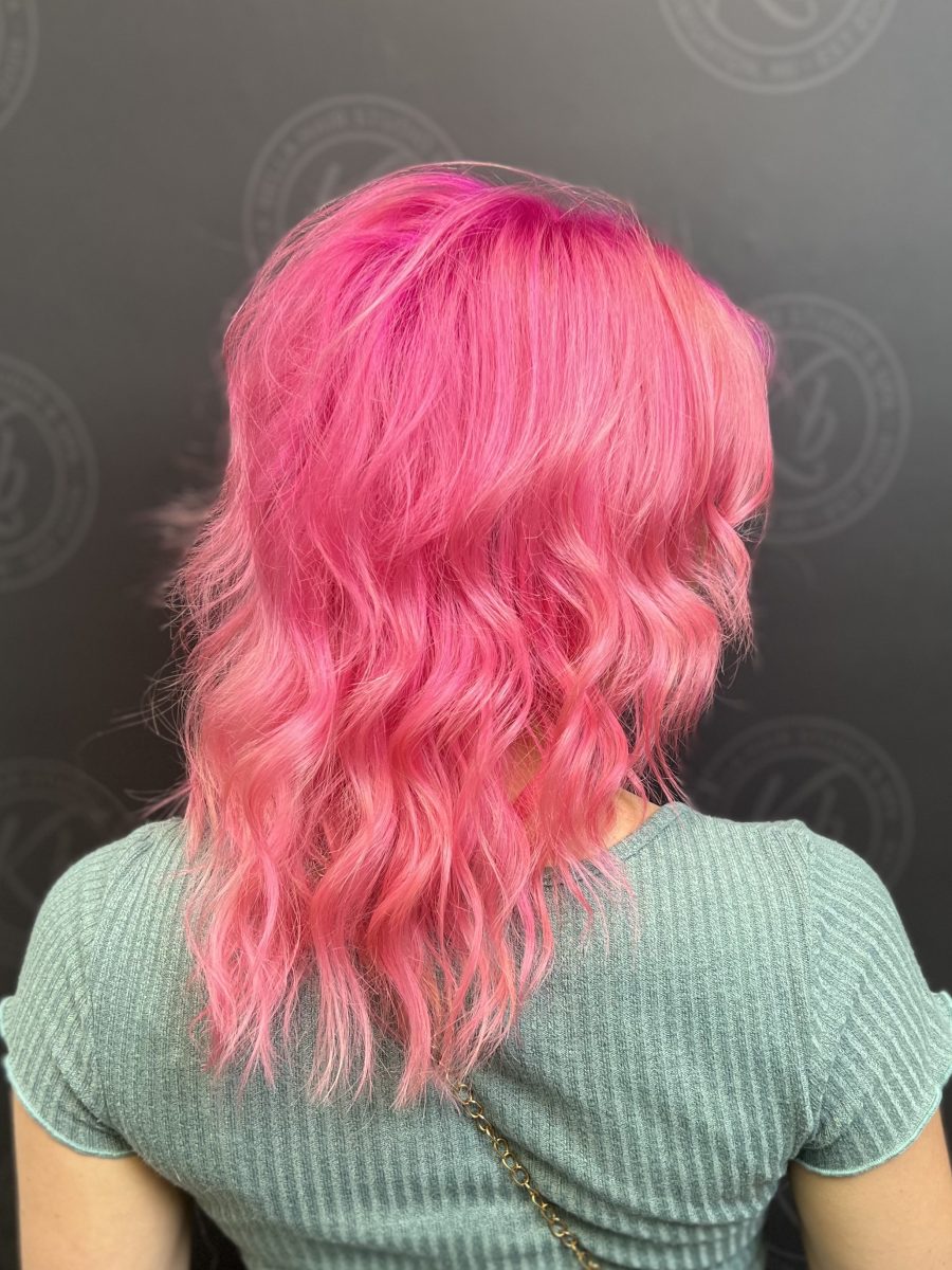 Back view of shoulder-length pink wavy hair with dimensional movement by Raquel Vettese at K Bella Hair Studio & Spa in Brighton, MI