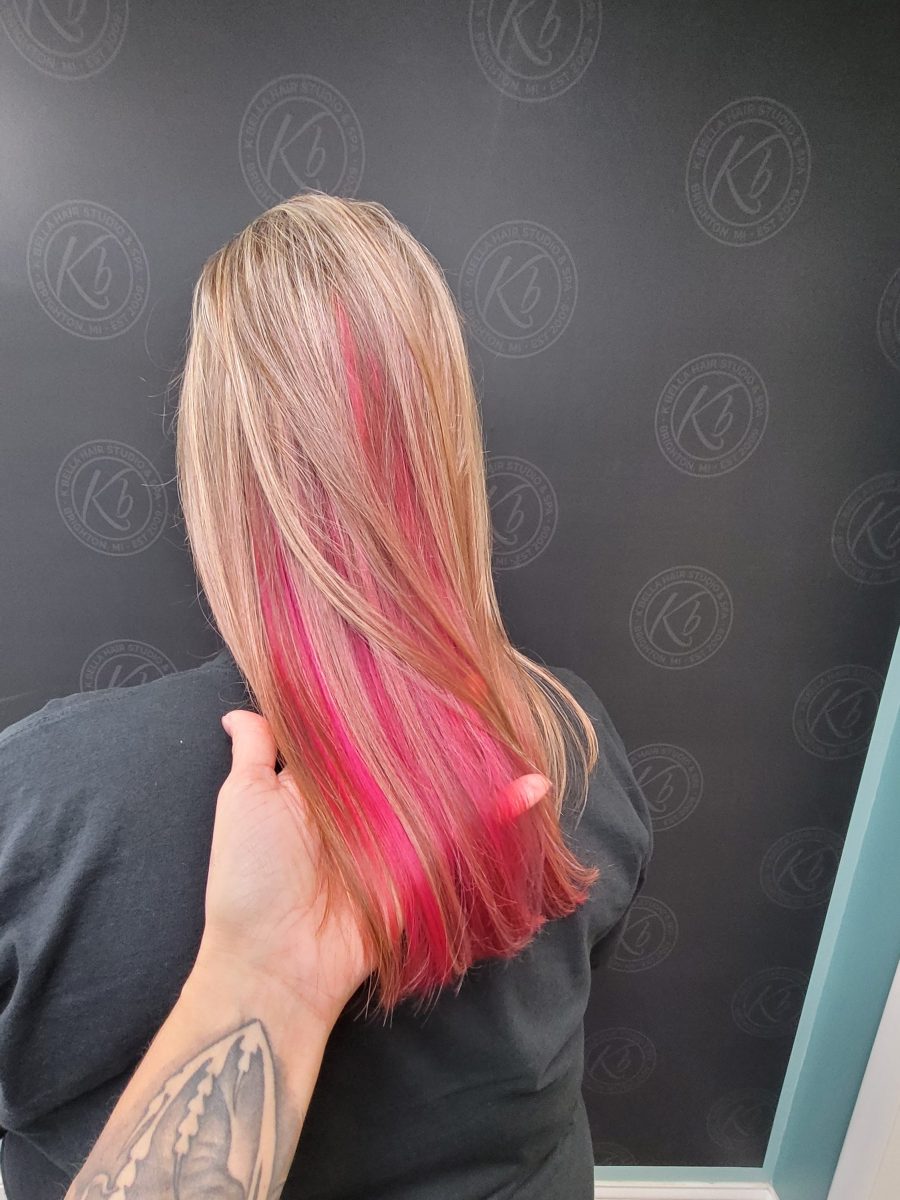 Back view of shoulder-length hair with beige blonde base color and hot pink peekaboo highlights visible through the length by Kristan Sayers at K Bella Hair Studio & Spa in Brighton, MI