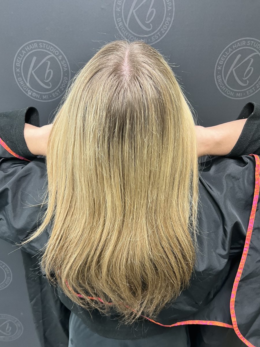 Back view of shoulder-length blonde hair before service by Raelynn Haan at K Bella Hair Studio & Spa in Brighton, MI