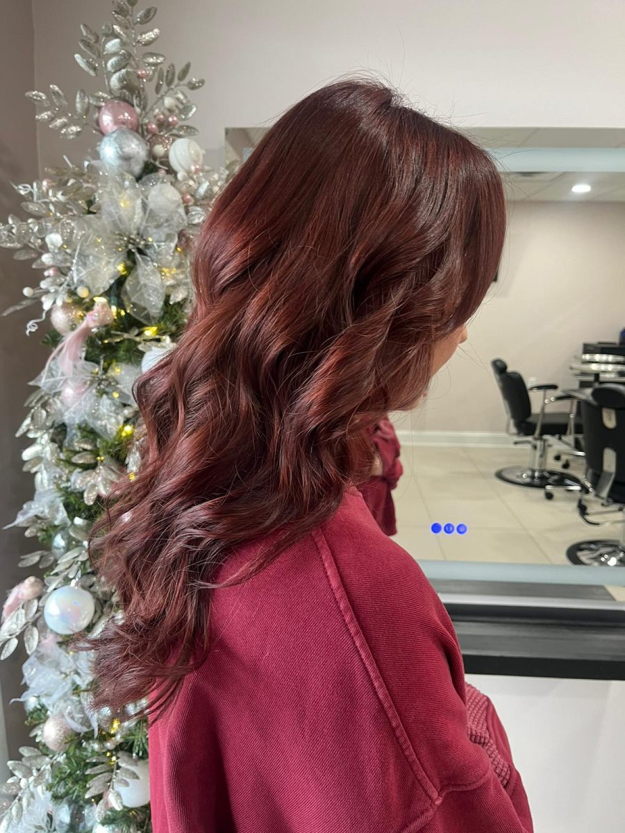 Side profile of long burgundy-red wavy hair with consistent color and movement, by Katie Rowe at K Bella Hair Studio & Spa in Brighton, MI